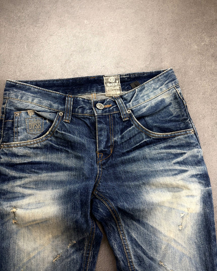 DPSR denim front close-up showing embroidered shield patch, button fly and whiskering
