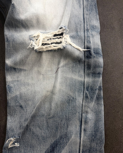 IMPROVES denim knee close-up showing open rip with white threads and indigo fading